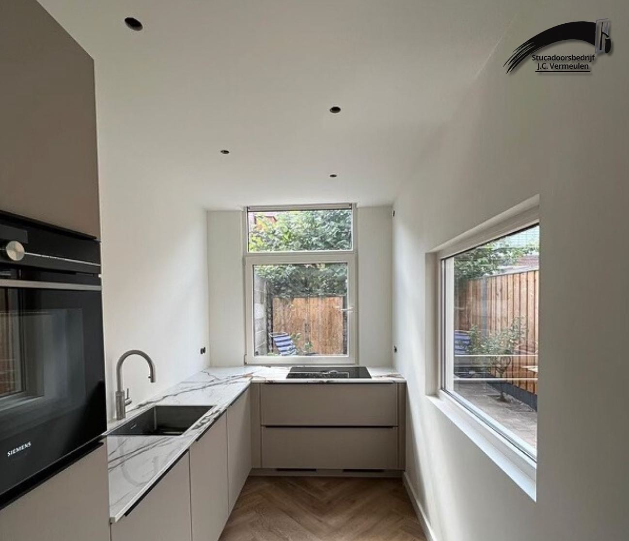 Dezelfde keuken na de renovatie, met strak gestucte witte wanden en een nieuwe keuken