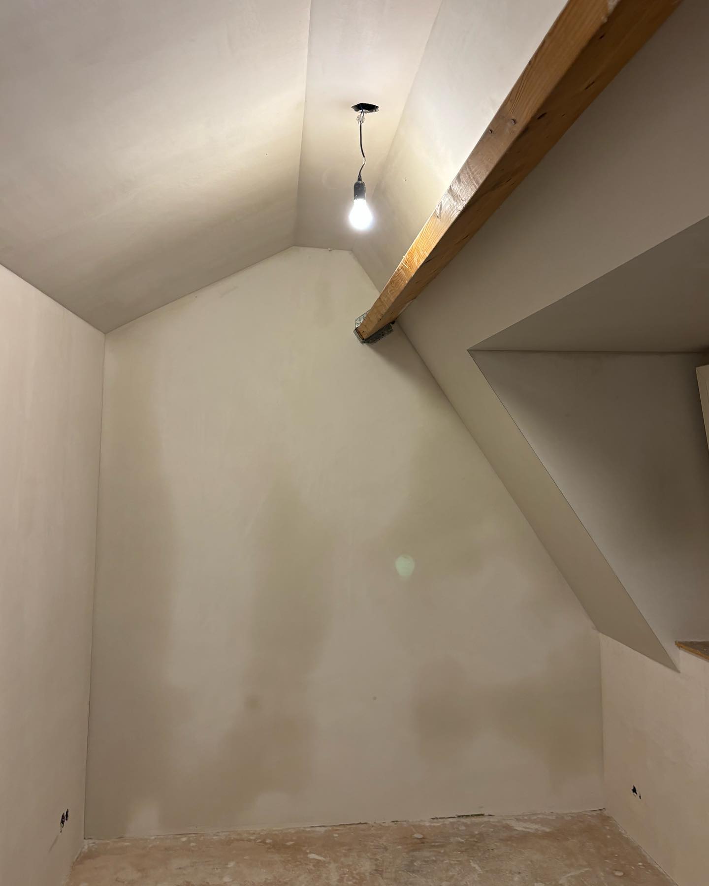 Glad gestucte zolderkamer met schuine wanden en een houten balk