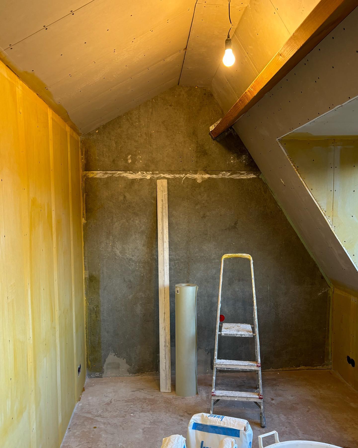 Zolderkamer voor het stucwerk, met kale gipsplaten, isolatie en een trapje
